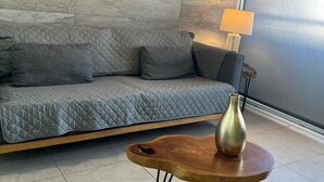 A modern living room with a grey sofa, a wooden coffee table, a vase, and a lamp. - Modern 2BR 2BA | Workspace Wifi | Pools | 24/7 Sec (Cancún)