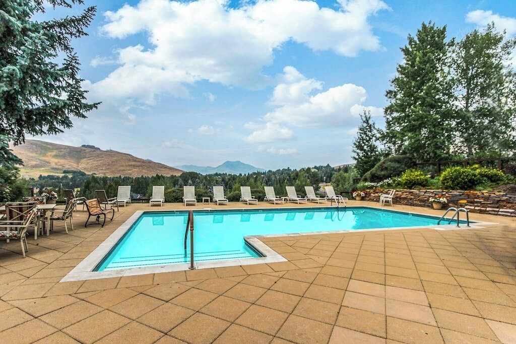 A rectangular pool with clear blue water, surrounded by a tiled patio with lounge chairs.