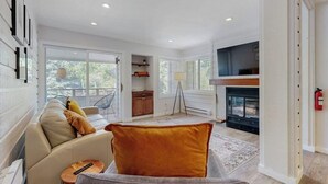 Un salon moderne comprenant un canapé, une table basse, une cheminée et un téléviseur.