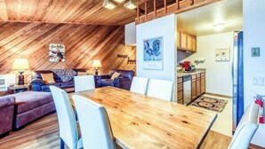 A cozy, wood-paneled room with a dining table, two sofas, and a kitchen area. - Mountain retreat with golf on-site (Sun Valley)