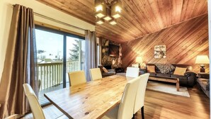 A cozy room with a wooden ceiling, a dining table with chairs, a sofa, and a TV mounted on the wall. - Mountain retreat with golf on-site (Sun Valley)