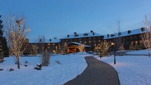 A snow-covered pathway leading to a building with multiple windows and a snow-covered roof.