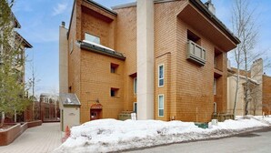 Un edificio de varios pisos con fachada de ladrillo, una entrada visible y suelo cubierto de nieve.