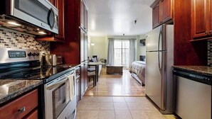 Una cocina equipada con microondas, estufa, horno y refrigerador. Hay un comedor con mesa y sillas.