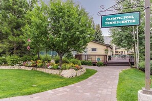 A pathway leading to a building labeled 'Olympic Pool Tennis Center' with a well-maintained lawn and a small garden area. - Charming condo w/ full kitchen, washer/dryer - close to ski slopes (Sun Valley)