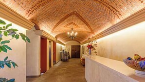 Un couloir avec un plafond en briques, un comptoir d’accueil et une plante sur le côté gauche.