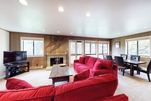 Ein Wohnzimmer mit einem roten Sofa, einem Fernseher, einem Kamin und einem Essbereich.