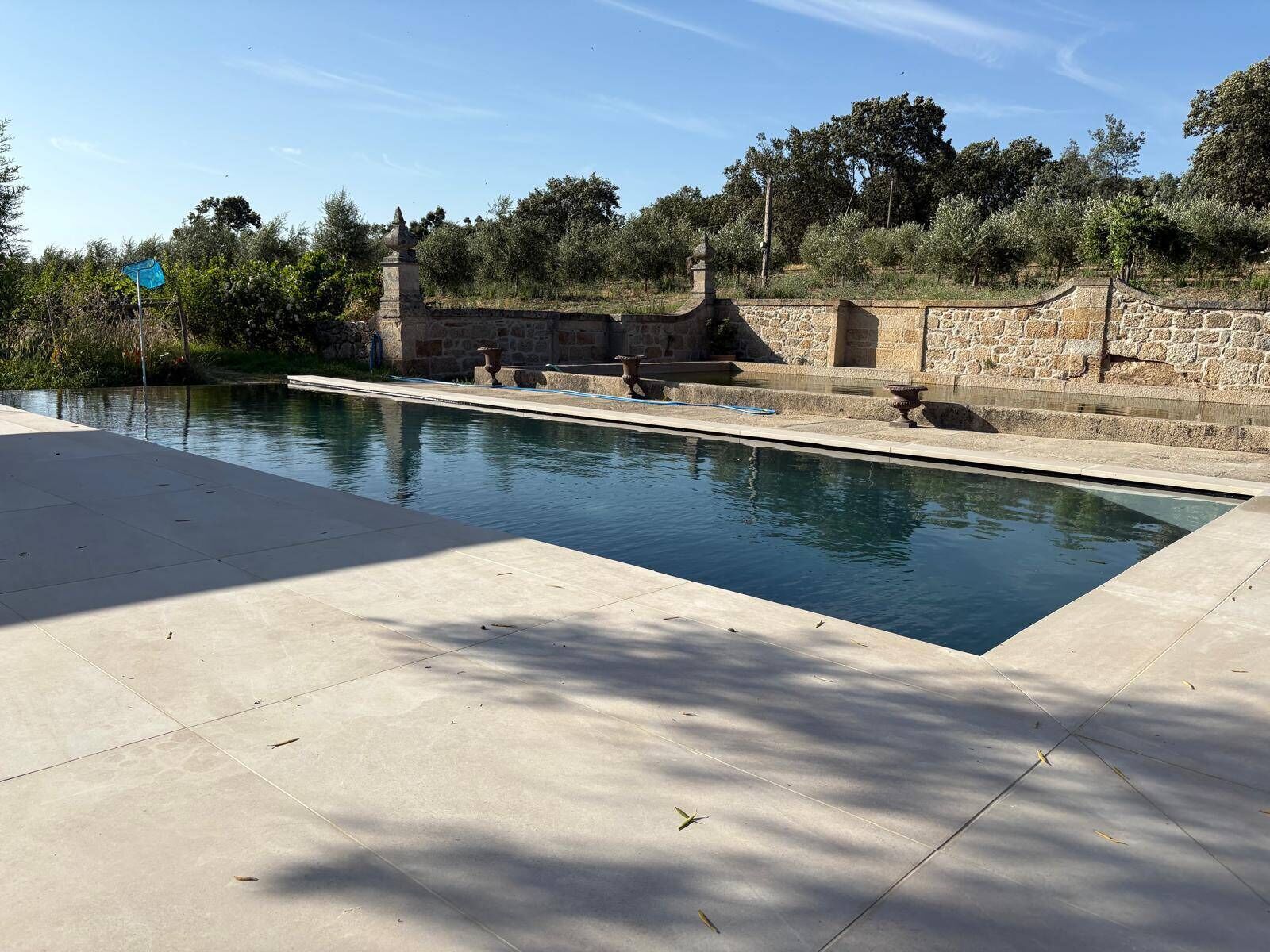 Ein rechteckiger Pool mit Steinwänden und einem Kiesweg, der darauf führt.