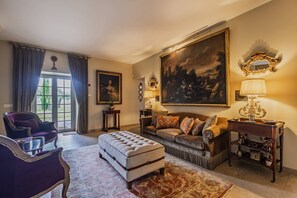 A living room with a sofa, ottoman, and a large painting on the wall.