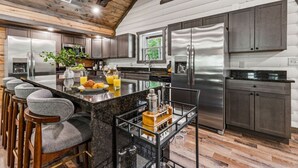 Una cocina moderna con electrodomésticos de acero inoxidable, una isla de mármol y taburetes de bar.