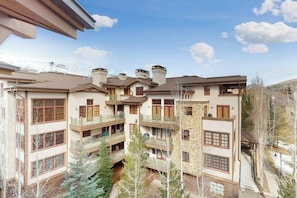 Un immeuble à plusieurs étages doté de balcons, d’une cour intérieure et surplombant un paysage montagneux.
