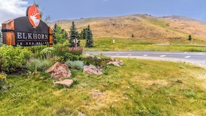 A sign for 'Elkhorn in Sun Valley' with a deer logo, surrounded by greenery and a road. - Modern mountain penthouse close to hikes & skiing (Sun Valley)
