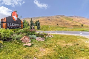 Une enseigne pour « Elkhorn in Sun Valley », avec un logo représentant un cerf, entourée de verdure et bordée par une route.