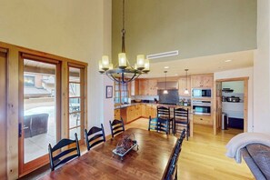 Un comedor amplio con una mesa y sillas de madera, un candelabro y vistas al exterior.