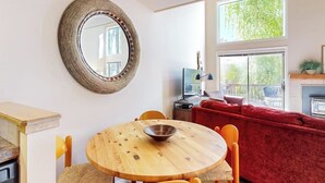 A dining area with a round wooden table, chairs, a woven mirror, and a red sofa. - Pleasant condo with private washer/dryer (Sun Valley)