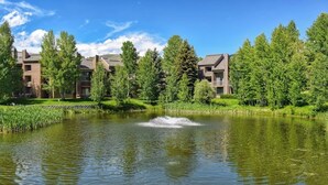 A tranquil pond with a fountain, surrounded by lush greenery and modern buildings. - Pleasant condo with private washer/dryer (Sun Valley)