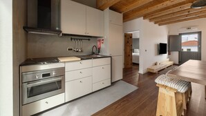 Een moderne keuken met roestvrijstalen apparatuur, houten balken en een grote eettafel.