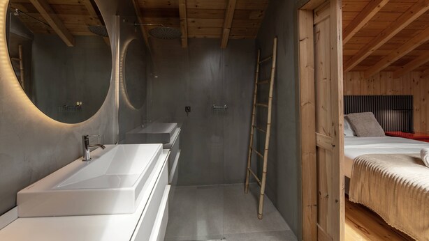Een moderne badkamer met een grote spiegel, een witte wastafel en een douchecabine.