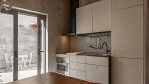 Een moderne keuken met een houten aanrecht, roestvrijstalen apparatuur en uitzicht op het buitenterras.