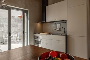 A modern kitchen with a wooden countertop, stainless steel appliances, and a view of the outdoor patio.