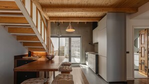 Een moderne keuken met houten balken, een eethoek met banken en uitzicht naar buiten.