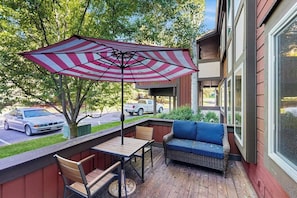 Une terrasse couverte avec une table, des chaises, un canapé et un parasol à rayures.