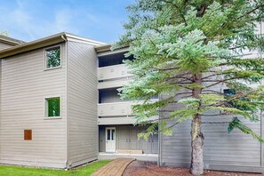 A multi-story building with a flat roof, a small front porch, and a tree in front.