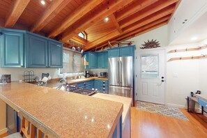 Eine Küche mit Granit Arbeitsplatten, Edelstahlgeräten und blauen Schränken.