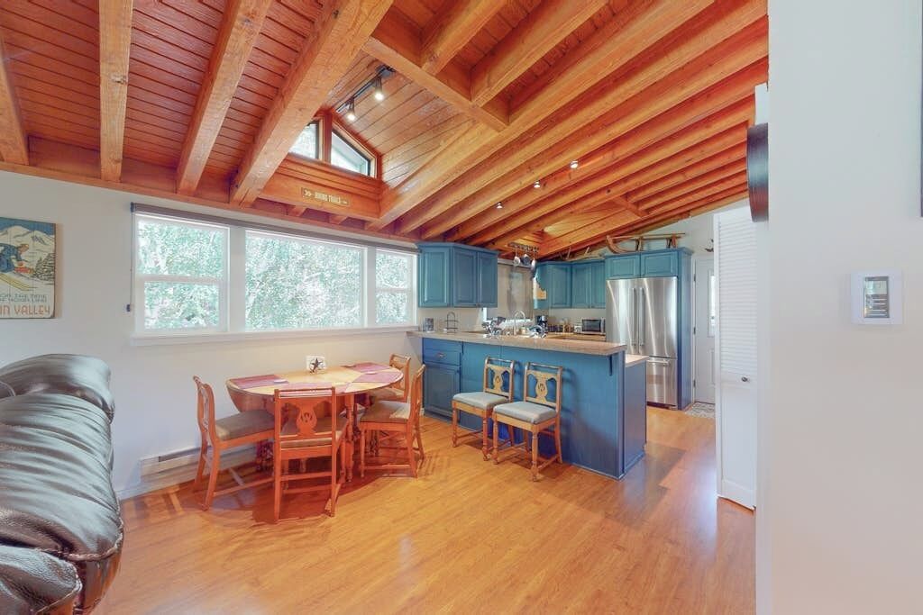A kitchen with wooden beams, a dining table with chairs, and a refrigerator.