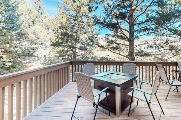 A deck with a grill, chairs, and a view of trees and buildings. - 3-Story Condo w/Balcony, Gas Fireplace, Deck, Washer/Dryer, Fast WiFi, & More (Sun Valley)