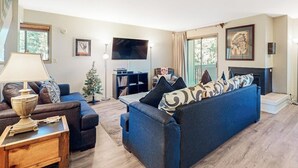 Una sala de estar con sofá, mesa de centro, televisor, chimenea y estantería.