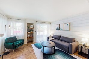 Ein modernes Wohnzimmer mit einer Couch, einem grünen Sessel, einem Couchtisch und einer Lampe.