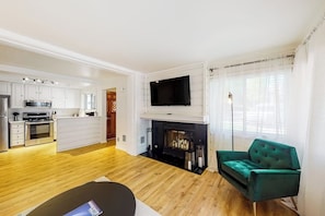 Ein modernes Wohnzimmer mit Kamin, Flachbildfernseher und einem grünen Sofa.