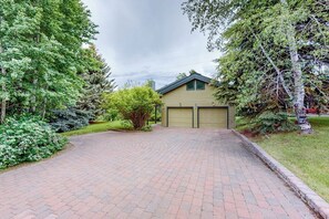 A residential driveway leading to a house with a garage, surrounded by lush greenery and trees. - Juniper Haven Retreat | Home in Sun Valley (Sun Valley)