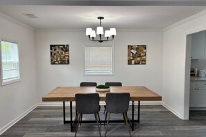 A dining area with a wooden table, four chairs, a chandelier, and two abstract paintings on the walls. - Cozy ATL Stay Fast Wi-Fi + Close to Everything (Atlanta)