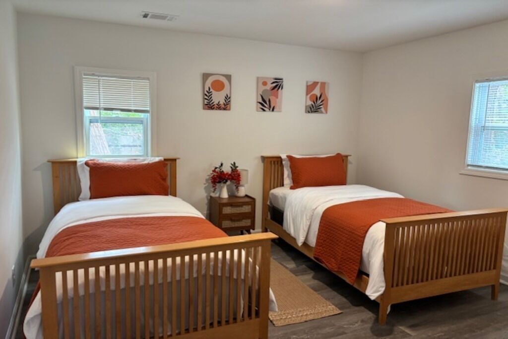 A bedroom with two wooden beds, a nightstand, and wall art.