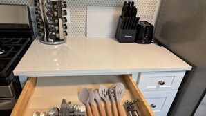 Una cocina con un cajón que contiene utensilios, un especiero y un tostador.