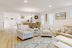 A spacious living area with striped armchairs, a sofa, a coffee table, and a rug. - Coastal retreat steps to the beach with smart TVs, desk, grill, children's items (Gloucester)