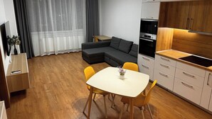 A modern kitchen with a dining area, a sofa, and a TV.