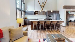 A modern kitchen with a central island, bar stools, pendant lights, and a deer antler decoration. - Inviting condo with skiing, pool, fireplace, mountain view, & W/D (Sun Valley)