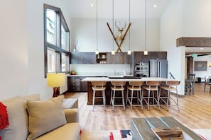 A modern kitchen with a central island, bar stools, pendant lights, and a deer antler decoration. - Inviting condo with skiing, pool, fireplace, mountain view, & W/D (Sun Valley)