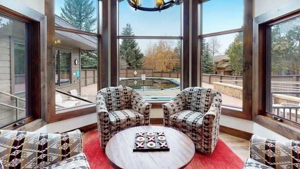 A room with large windows, two patterned armchairs, a small round table, and a red rug. - Inviting condo with skiing, pool, fireplace, mountain view, & W/D (Sun Valley)
