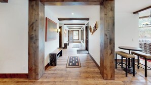 A hallway with wooden beams, a bench, a rug, and a table with stools. - Inviting condo with skiing, pool, fireplace, mountain view, & W/D (Sun Valley)