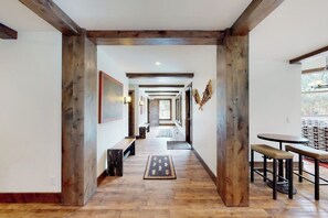 A hallway with wooden beams, a bench, a rug, and a table with stools. - Inviting condo with skiing, pool, fireplace, mountain view, & W/D (Sun Valley)