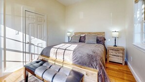 A bedroom with a bed, bedside tables, a bench, and a door.