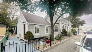 A two-story house with a grey roof, white siding, and a black metal fence.
