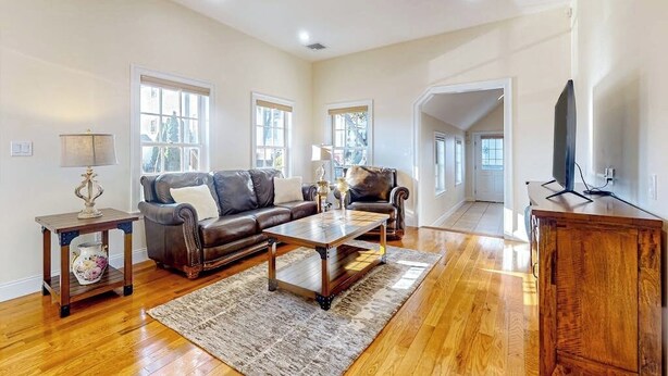 A spacious living room with a leather sofa, a coffee table, and a television.