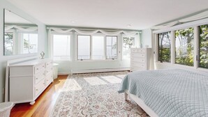 Un dormitorio con cama, cómoda y ventanas amplias.