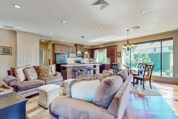 A spacious living area with a sofa set, a dining table with chairs, and a kitchen area with a bar. - Centrally located open concept apartment with parking, central AC, & W/D (Gloucester)