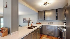 A modern kitchen with grey cabinets, a white countertop, and stainless steel appliances. - Gorgeous mountain retreat with pool, hot tub, games, & golf - walk-to-lifts (Sun Valley)